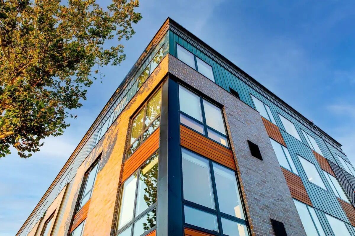 Un bâtiment moderne doté de grandes fenêtres et d’une façade combinant brique et verre.