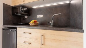 Eine moderne Küche mit Holzschränken, einem Edelstahl-Geschirrspüler, einer schwarzen Dunstabzugshaube und einer Obstschale auf der Arbeitsplatte.