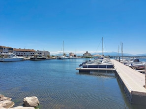 A marina with boats docked, a pier, and buildings in the background.
