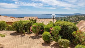 A courtyard with tiled roofs, a spherical street lamp, and lush greenery. - Nice apartment for 2 guests with pool, WIFI, TV and balcony (Roquebrune-sur-argens)