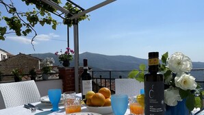 A table set outdoors with a view of the sea and mountains.