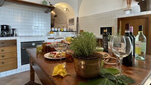 A kitchen with white tiles, a wooden counter, a potted plant, wine bottles, and a decorative figure.