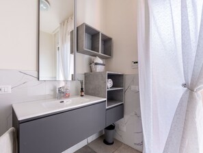 A modern bathroom with a white marble sink, grey cabinets, and a large mirror. - Cosy apartment for 6 people with A/C, hot tub, WIFI, TV, terrace and pets allowed (Varazze)
