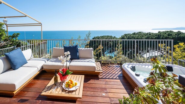 A wooden deck with a sofa, a hot tub, and a table with fruits and a bottle. - Nice apartment for 6 guests with WIFI, A/C, hot tub, TV, terrace and pets allowed (Varazze)
