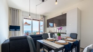 A modern living room with a sofa, dining table, and kitchen area. - Nice apartment for 6 guests with WIFI, A/C, hot tub, TV, terrace and pets allowed (Varazze)