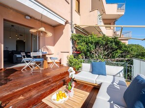 A wooden deck with outdoor furniture, a sofa, and a dining table with a fruit plate. - Cosy apartment for 6 people with A/C, hot tub, WIFI, TV, terrace and pets allowed (Varazze)