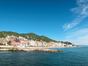 A coastal town with buildings along the waterfront, a rocky breakwater, and a hill in the background. - Cosy apartment for 6 people with A/C, hot tub, WIFI, TV, terrace and pets allowed (Varazze)
