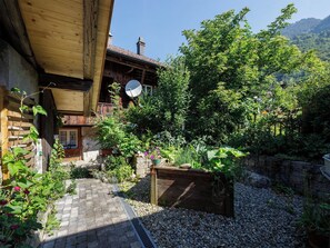 A rustic wooden building with a satellite dish, surrounded by lush greenery and a gravel path. - Lovely apartment for 4 people with WIFI, TV, terrace, pets allowed and panoramic view (Brienzwiler)