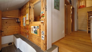 Interior de madeira com balcão de recepção, um espelho e uma porta que dá para outro cômodo.