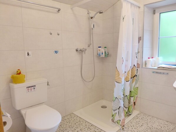 Une salle de bain équipée de toilettes, d’une douche et d’une fenêtre donnant sur un beau paysage.
