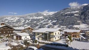 A snow-covered mountain village with traditional wooden houses and modern buildings, surrounded by snow-covered hills and a clear blue sky. - Beautiful private villa for 22 guests with WIFI, TV, patio and pets allowed (Fügen)