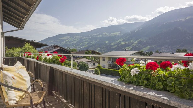 A wooden balcony with a wicker chair and flower boxes, overlooking a mountain landscape. - Beautiful private villa for 22 guests with WIFI, TV, patio and pets allowed (Fügen)