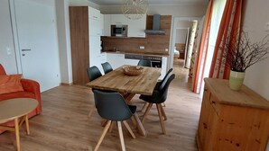 A modern kitchen with white cabinets, a wooden dining table, and black chairs.