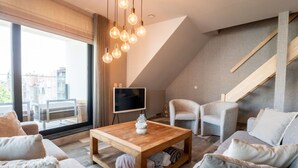 Un salon moderne avec une table basse en bois, des canapés gris et un téléviseur posé sur un meuble.