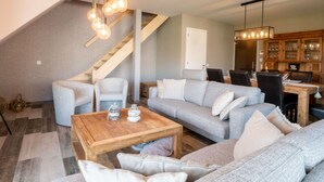 Un salon moderne avec un canapé gris, une table basse en bois et un escalier.
