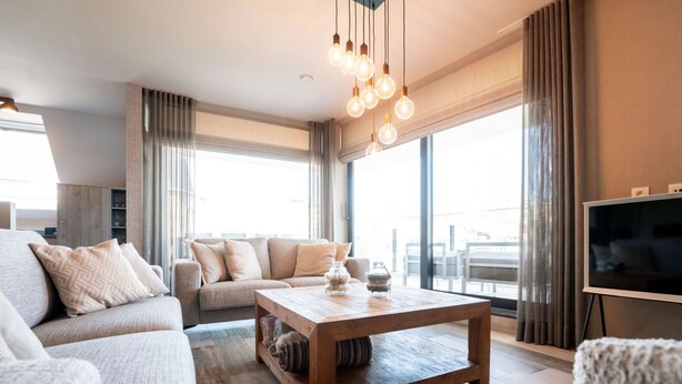 Un salon moderne avec un canapé, une table basse et un téléviseur.