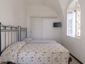 Cozy retreat with a single bed, television, and floral-patterned bedspread.