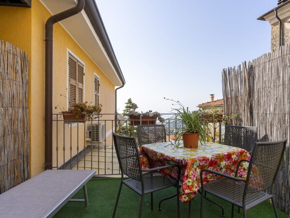 Relax on the patio with a table and four chairs, surrounded by potted plants.