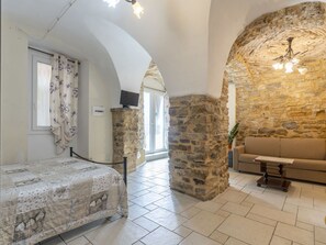 Cozy retreat with a stone wall, patterned bedspread, and comfortable sofa.