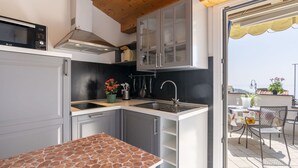 A compact kitchen with a stone countertop, a built-in stove, and a sink. - Cosy apartment for 4 guests with A/C, WIFI, balcony and panoramic view (Terzorio)