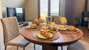 A dining area with a round table set for breakfast, including croissants, eggs, and coffee.