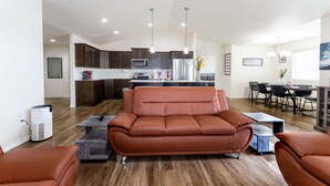 A modern living room with a brown leather sofa, a dining area with a table and chairs, and a kitchen with dark cabinets and stainless steel appliances. - 3 King Beds • Luxury Quiet Stay • Modern & Clean Near Spokane Airport & Casino (Spokane)