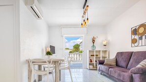 A modern living room with a dining area, a purple sofa, a TV, and a decorative shelf.