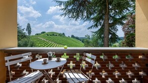 Ein Balkon mit einem weißen Tisch und Stühlen, einer Kaffeekanne und einem Glas Orangensaft.
