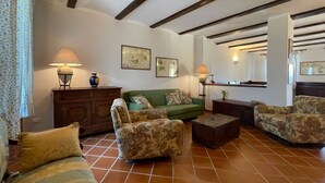 Ein Wohnzimmer mit einem grünen Sofa, floralen Sessel, einem Holzschrank und einem Fliesenboden.