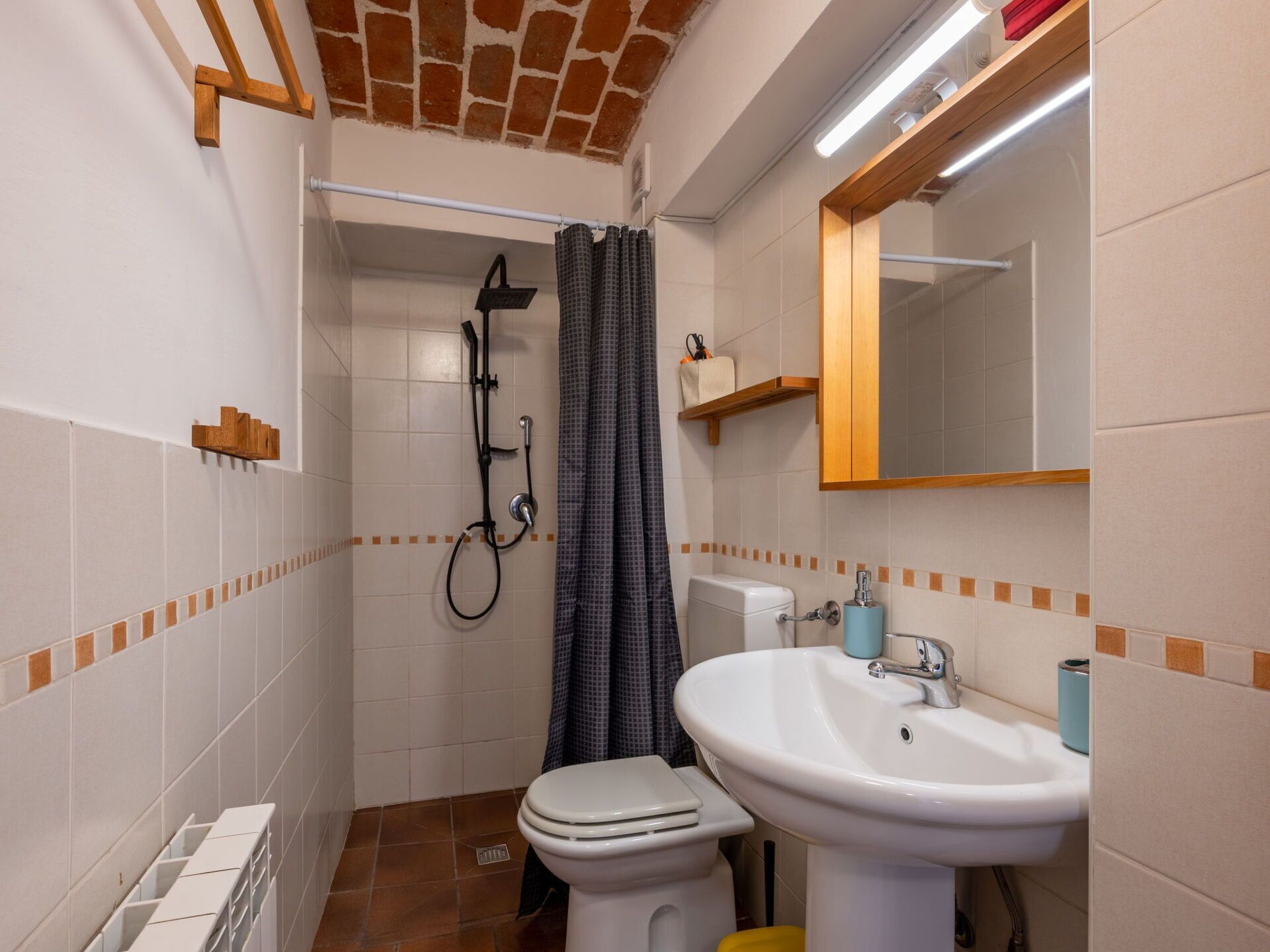 Een kleine badkamer met douche, toilet en wastafel.