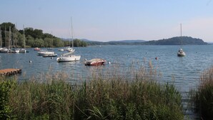 Ein ruhiger See mit mehreren Segelbooten, die an einem Steg festgemacht sind.