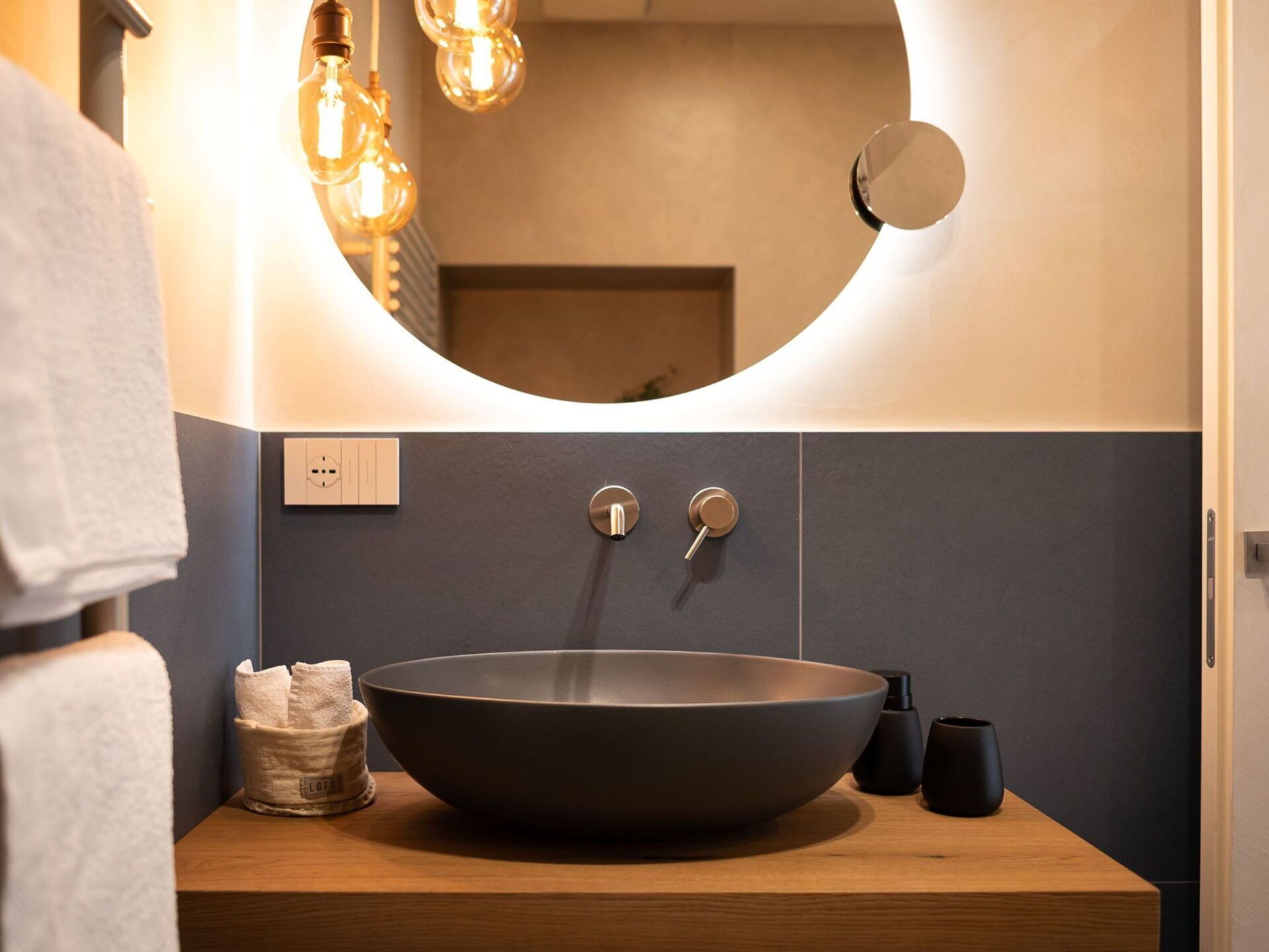 A bathroom with a round sink, a mirror, and a towel rack.