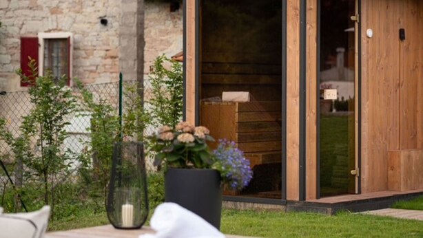 A wooden structure with a sliding door, a stone building in the background, and a garden with a table and a vase. - Beautiful private villa for 3 people with private pool, WIFI and TV (Farra D'alpago)