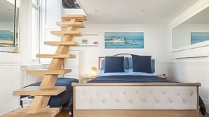 Une chambre à coucher avec un lit, un escalier en bois et un tableau accroché au mur.