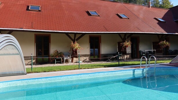 A hotel with a swimming pool, outdoor seating, and a red brick roof. - Beautiful apartment for 4 people with pool, WIFI, TV and patio (Jablonec Nad Nisou)