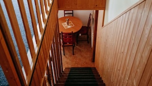 A wooden staircase leading to a dining area with a round table and chairs. - Beautiful apartment for 4 people with pool, WIFI, TV and patio (Jablonec Nad Nisou)