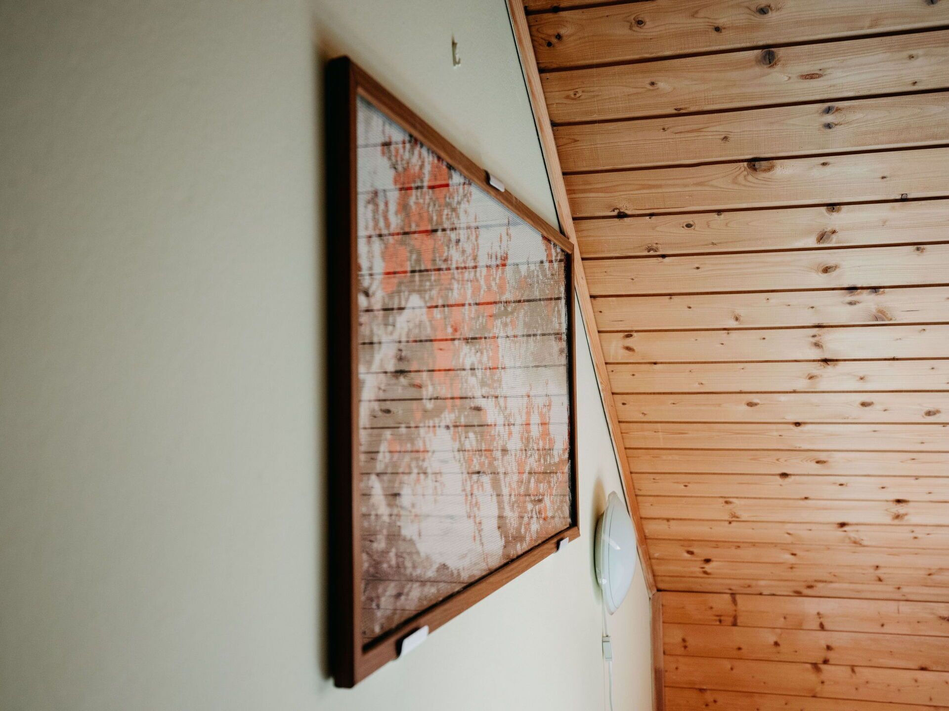 A room with a wooden ceiling and a framed artwork on the wall.