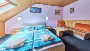 Ett mysigt rum med ett sluttande tak, en säng med blått sänglinne, en träbänk och ett litet bord.