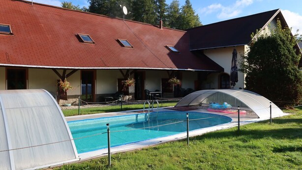 Ett hus med en swimmingpool, en inglasad uteplats och ett rött tak.