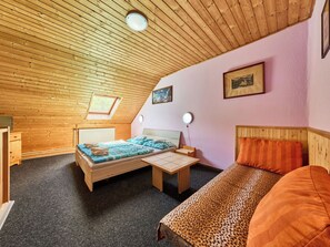 A bedroom with a sloped ceiling, a bed with a leopard print cover, a small table, and a nightstand.