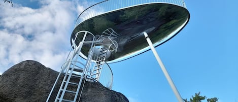 Estructura de antena parabólica montada sobre una roca con una escalera de caracol.