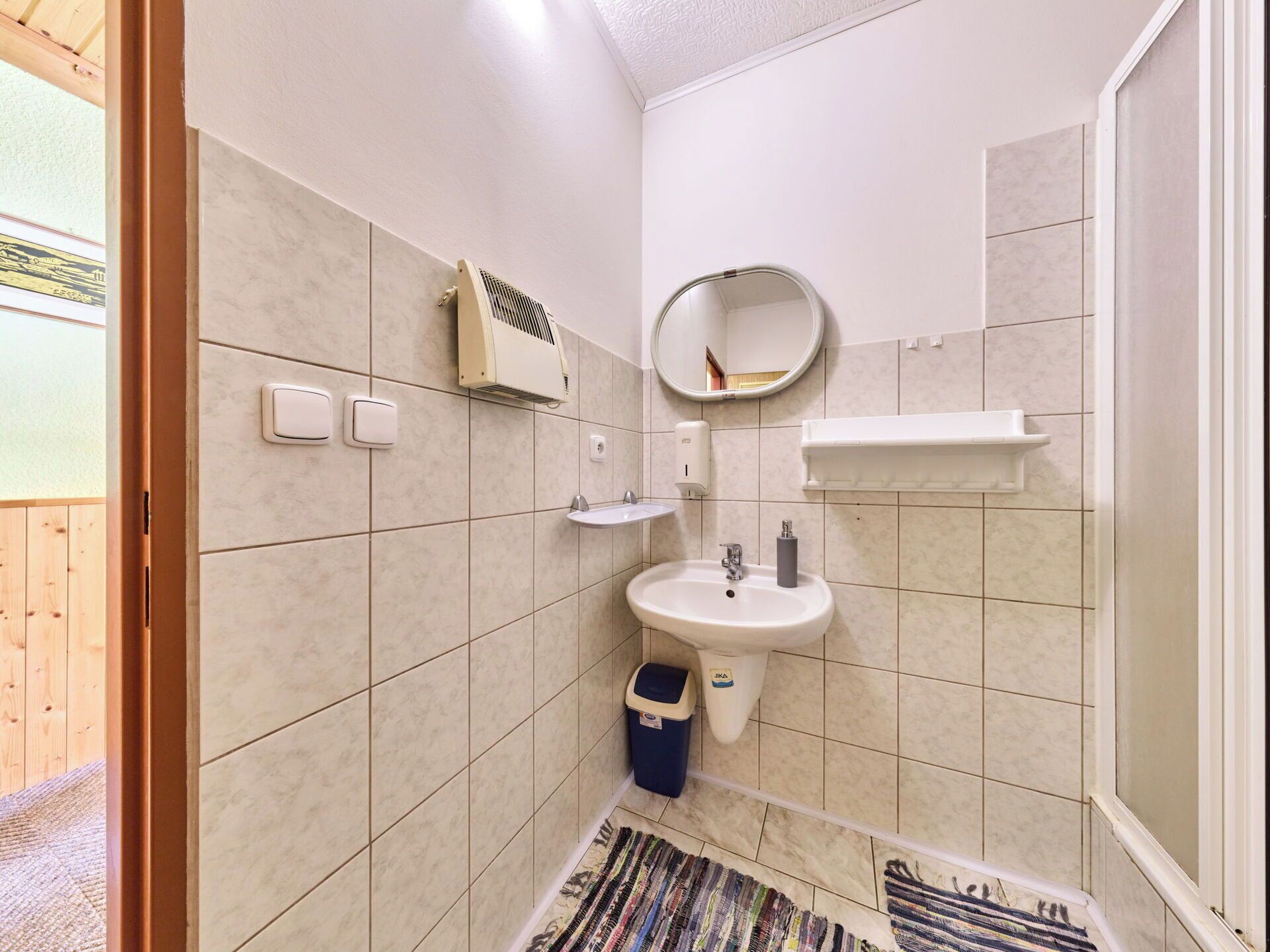 Une salle de bain équipée d’un lavabo, d’un miroir, d’un porte-serviettes et d’une poubelle.