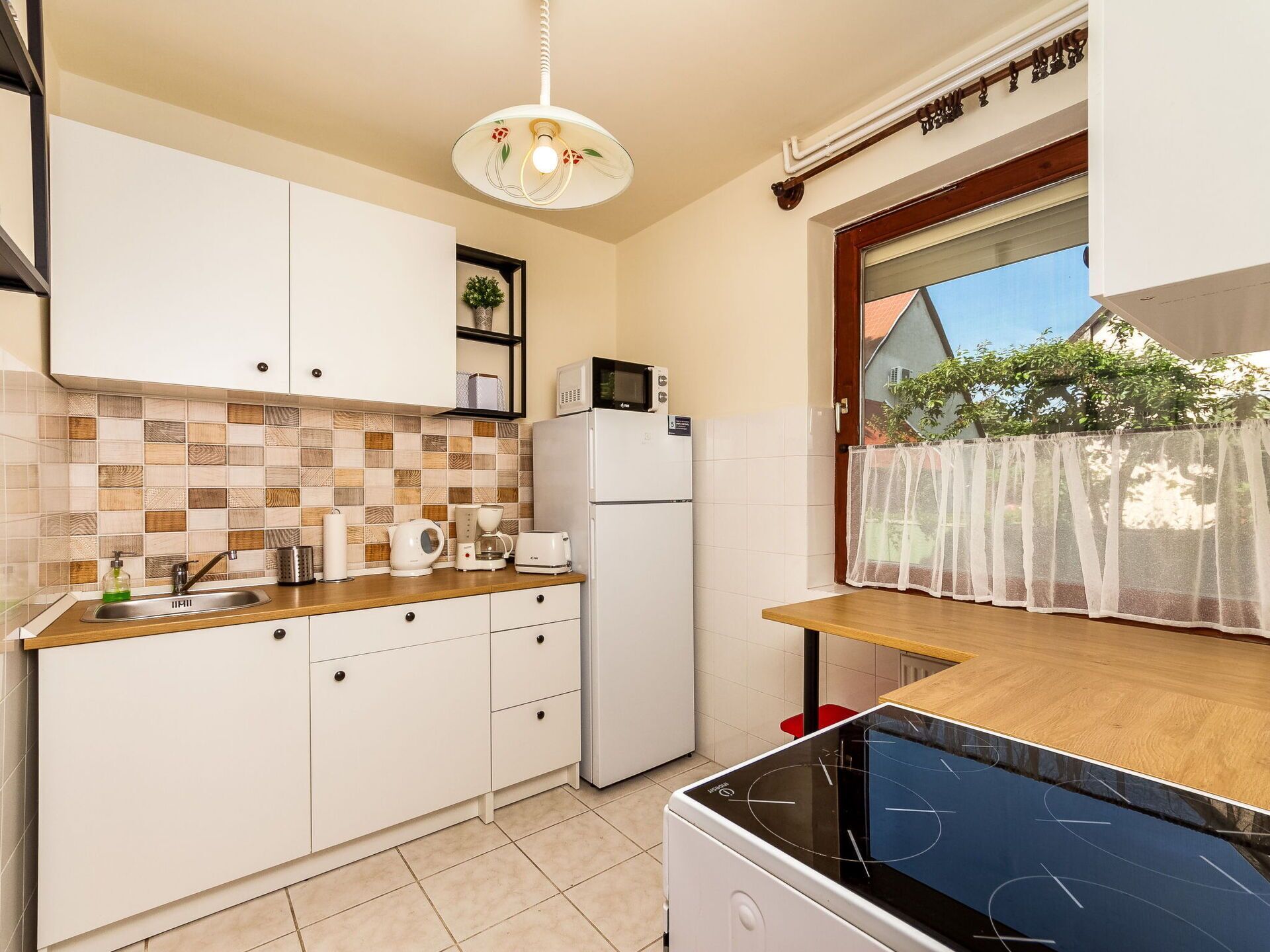 A compact kitchen with white cabinets, a microwave, a refrigerator, and a sink.