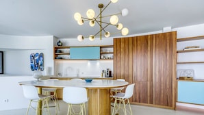 A modern kitchen with a central island, white chairs, and a unique chandelier. - Beautiful private villa for 8 guests with WIFI, private pool, A/C, TV and terrace (Roses)