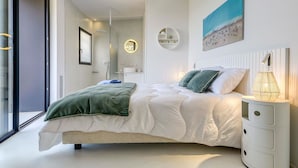 A modern bedroom with a large bed, a bedside table with a lamp, a round mirror, and a painting on the wall. - Beautiful private villa for 8 guests with WIFI, private pool, A/C, TV and terrace (Roses)