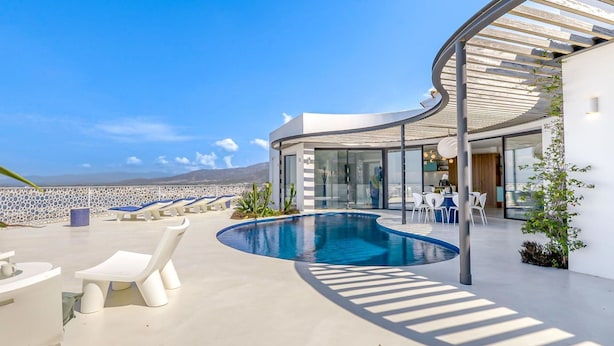 A modern outdoor pool area with lounge chairs and a curved glass structure. - Beautiful private villa for 8 guests with WIFI, private pool, A/C, TV and terrace (Roses)