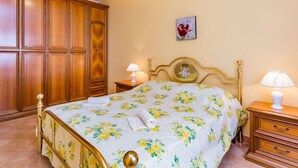 A bedroom with a bed, wooden wardrobe, bedside tables, and a wall-mounted picture.