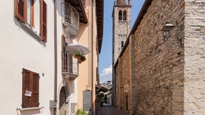 A narrow street with stone buildings, a church tower, and a balcony with hanging plants. - Cosy apartment for 4 people with WIFI and balcony (Domaso)
