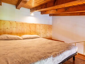Un dormitorio con cabecera de madera, cama con colcha estampada y techo de madera.