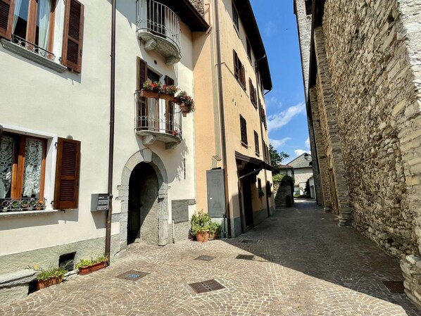 Una estrecha calle adoquinada bordeada por edificios históricos con fachadas de piedra y contraventanas de madera.